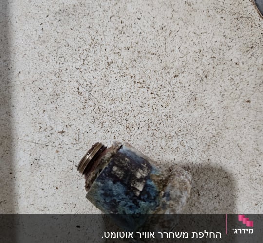 חלק מתכתי חלוד עם הברגה על משטח בהיר